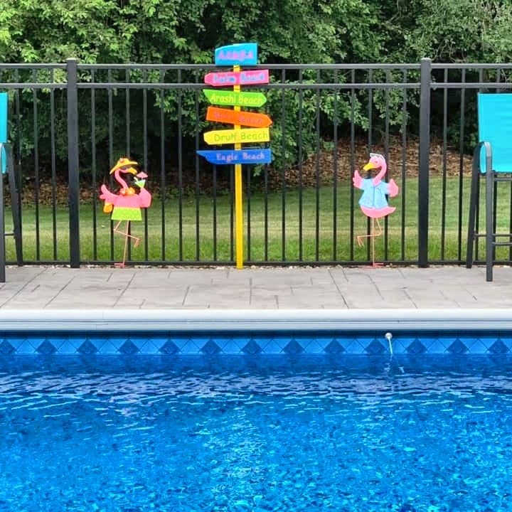 An Aruba sign beside a pool with two flamingo ornaments
