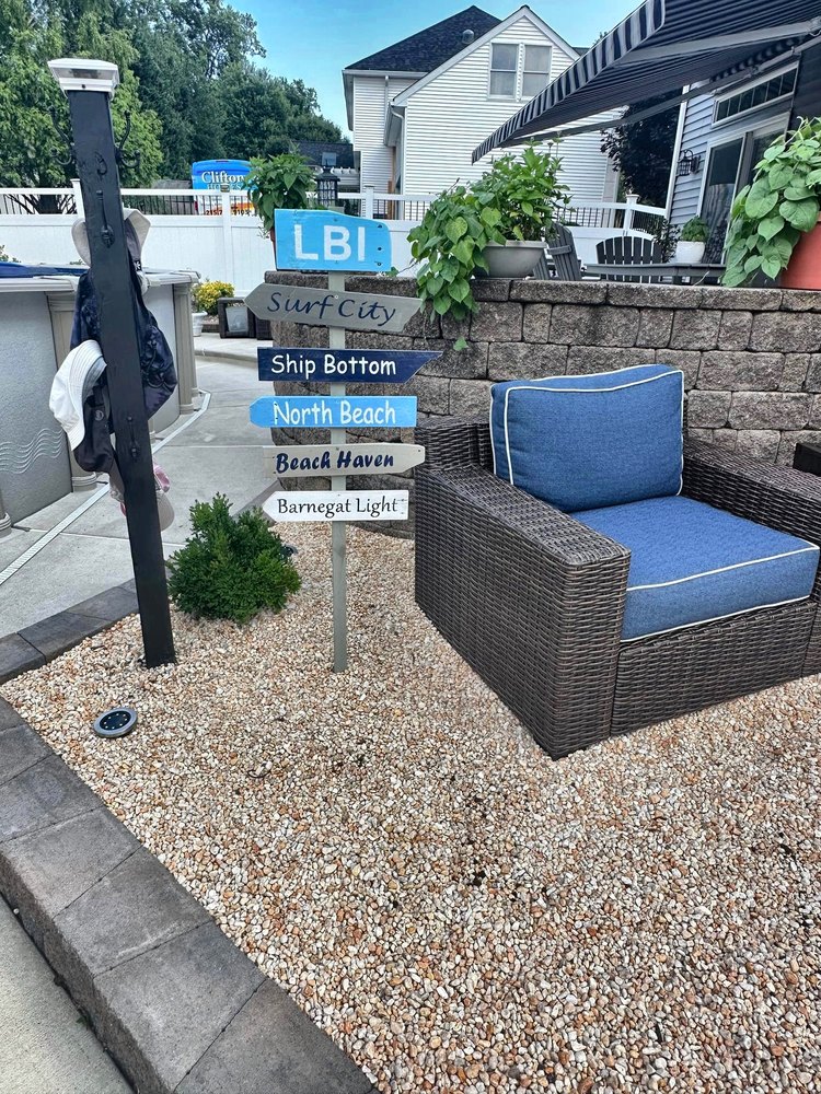 A hand-painted LBI directional sign standing in a Long Beach Island backyard