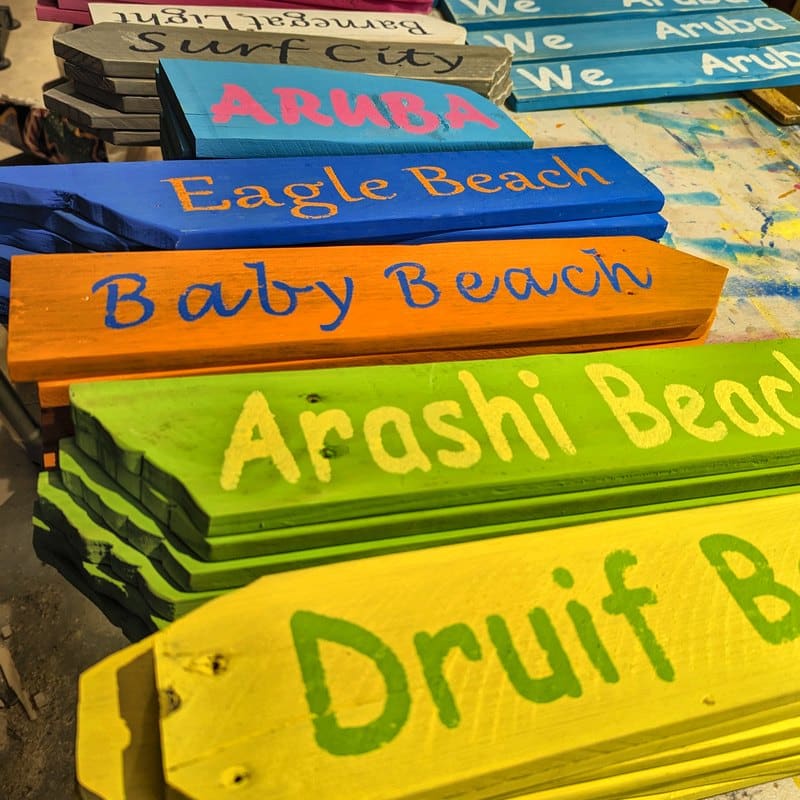 Finished hand-lettered beach arrows stacked before shipping